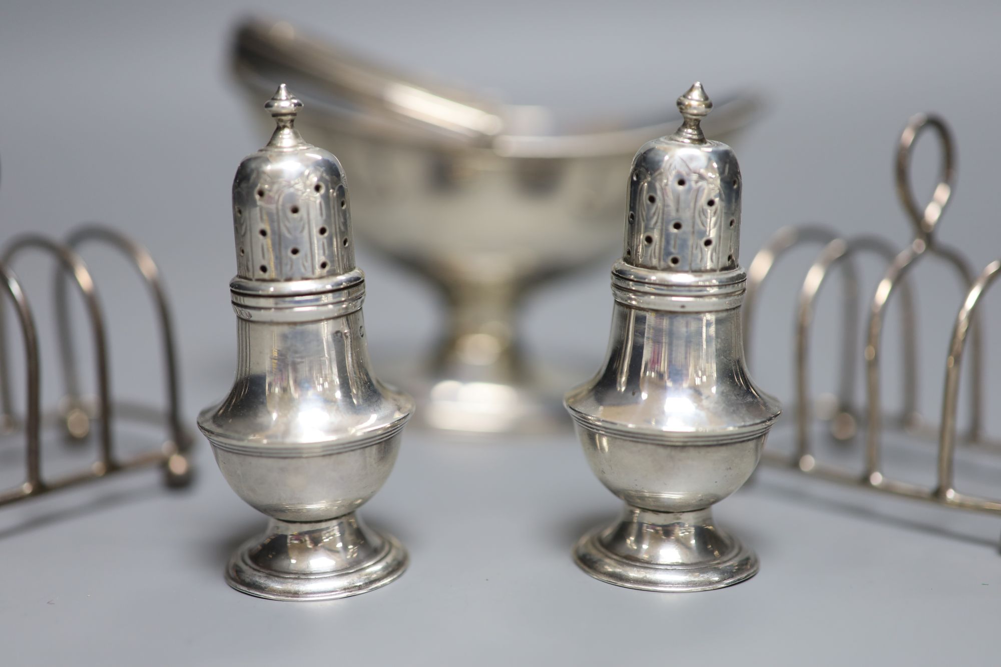 A small George III silver basket, London, 1785, a pair of Victorian silver peppers and a pair of later silver toastracks, 6.5oz.